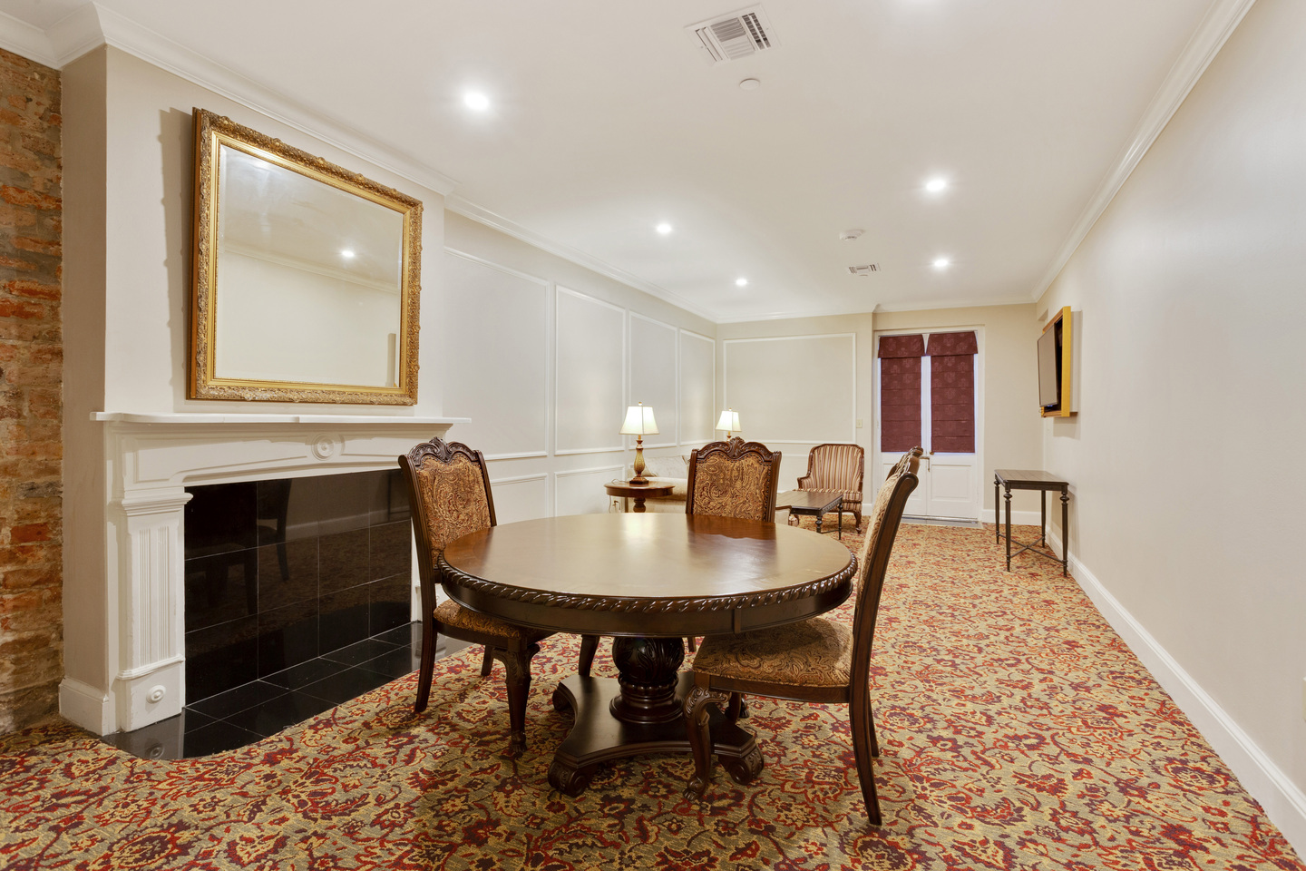 A formal dining area with a fireplace, a large mirror, and a dining table with chairs.